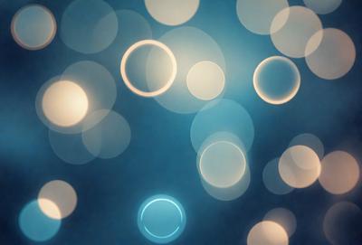 The primary subject of the image is a blue background with a pattern of white circles. The setting appears to be a dark room, and the visual style is a close-up of the circles. The dominant colors are blue and white, creating a calm and serene atmosphere.