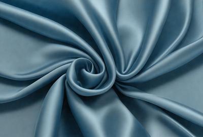 The primary subject of the image is a blue fabric, possibly a piece of silk, with a swirling pattern. The setting is a blue background, which complements the fabric's color. The visual style appears to be a close-up of the fabric, showcasing its texture and pattern. The colors and mood of the image are predominantly blue, creating a calm and serene atmosphere.