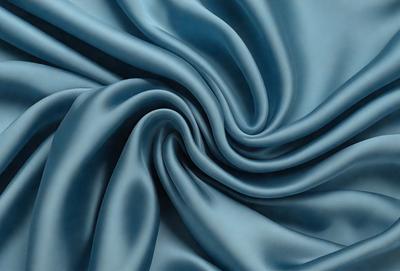 The primary subject of the image is a blue fabric, which appears to be a piece of silk. The setting is a blue background, and the visual style is a close-up of the fabric. The colors and mood of the image are predominantly blue, creating a calm and serene atmosphere.