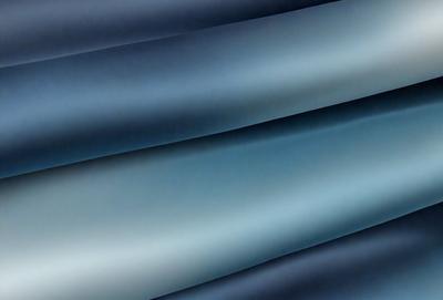 The primary subject of the image is a long, blue, metallic ribbon. The ribbon is wound up and appears to be made of metal. The setting is a dark room, and the visual style is a close-up of the ribbon. The dominant colors are blue and black, creating a moody atmosphere.