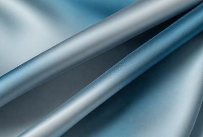 The primary subject of the image is a pair of silver wires. The setting is a blue surface, which could be a table or a wall. The visual style is a close-up of the wires, showcasing their texture and details. The colors and mood of the image are predominantly silver and blue, creating a calm and serene atmosphere.