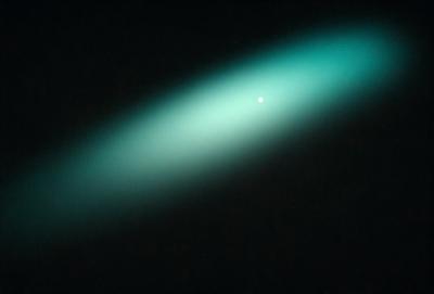 The primary subject of the image is a green light, which appears to be a neon light. The light is shining brightly, creating a visually striking scene. The setting is a dark room, which contrasts with the bright green light. The visual style of the image is a close-up of the green light, emphasizing its vibrant color and intensity. The overall atmosphere of the image is one of intrigue and fascination, as the viewer is drawn to the captivating glow of the green light.