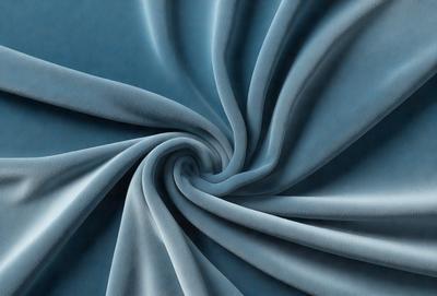 The primary subject of the image is a blue fabric, which appears to be a piece of cloth or a curtain. The setting is a dark blue background, which contrasts with the blue fabric. The visual style is a close-up of the fabric, showcasing its texture and pattern. The colors and mood of the image are predominantly dark and moody, with the blue fabric serving as the focal point.