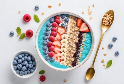 The primary subject of the image is a bowl filled with a variety of fruits and nuts, including blueberries, bananas, strawberries, and almonds. The bowl is placed on a white surface, which serves as the setting for the scene. The visual style of the image is a close-up of the bowl, showcasing the vibrant colors and textures of the fruits and nuts. The overall atmosphere of the image is fresh, healthy, and inviting, with