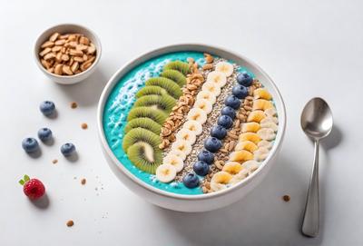 The primary subject of the image is a bowl filled with a variety of fruits and nuts. The bowl is placed on a white surface, which serves as the setting. The visual style of the image is a close-up of the bowl, showcasing the different fruits and nuts. The colors and mood of the image are vibrant and lively, as the bowl contains a mix of blueberries, bananas, kiwi, and walnuts. The overall atmosphere is fresh and health