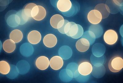 The primary subject of the image is a blue background with a pattern of white lights. The setting appears to be a nighttime scene, possibly a cityscape or a dark room with a light source. The visual style of the image is a combination of a photo and digital art, creating a unique and captivating atmosphere. The dominant colors are blue and white, with the white lights creating a sense of depth and contrast against the dark blue background.
