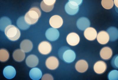 The primary subject of the image is a cluster of bright, white lights. The setting is a dark background, which contrasts with the bright lights. The visual style is a close-up of the lights, creating a pattern of circles. The colors and mood of the image are predominantly white, creating a clean and serene atmosphere.