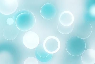 The primary subject of the image is a collection of round, blue glass balls. The setting is a white background, which creates a clean and minimalist appearance. The visual style is a close-up of the glass balls, showcasing their unique shapes and colors. The dominant colors are blue and white, giving the image a calm and serene atmosphere.
