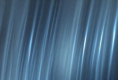 The primary subject of the image is a blue background with a pattern of light streaks or lines. The setting appears to be a dark room, and the visual style is a combination of a photo and digital art. The colors and mood of the image are predominantly blue, creating a calm and serene atmosphere.
