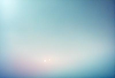 The primary subject of the image is a pair of bright lights in the sky, which appear to be two stars. The setting is a cloudy sky, and the visual style is a photo. The dominant colors are blue and white, creating a calm and serene atmosphere.