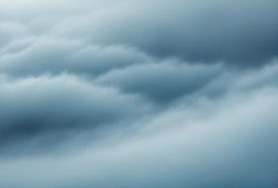 The primary subject of the image is a cloudy sky with a blue hue. The setting is a cloudy day, and the visual style is a natural, outdoor scene. The colors and mood of the image are predominantly blue, creating a calm and serene atmosphere.