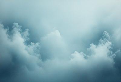 The primary subject of the image is a cloudy sky. The setting is a blue cloudy sky with a few clouds scattered throughout. The visual style is a photo of the cloudy sky. The colors and mood of the image are predominantly blue, with a slightly gloomy atmosphere.