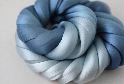 The primary subject of the image is a blue yarn ball. The setting is a white background, and the visual style is a close-up of the yarn ball. The dominant colors are blue and white, creating a calm and soothing atmosphere.