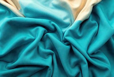 The primary subject of the image is a blue fabric, which appears to be a piece of cloth or a blanket. The setting is a room with a blue background, which complements the blue fabric. The visual style is a close-up of the fabric, showcasing its texture and details. The colors and mood of the image are predominantly blue, creating a calm and soothing atmosphere.