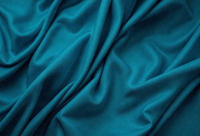The primary subject of the image is a blue fabric, which appears to be a piece of silk. The setting is a blue background, which complements the blue fabric. The visual style is a close-up of the fabric, showcasing its texture and details. The colors and mood of the image are predominantly blue, creating a calm and serene atmosphere.