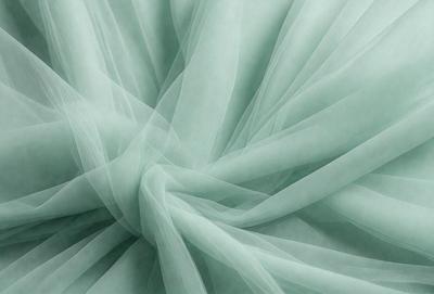 The primary subject of the image is a green fabric, possibly a curtain or a piece of clothing. The setting is a close-up of the fabric, showcasing its texture and details. The visual style is a close-up, which emphasizes the fabric's texture and intricate patterns. The colors and mood of the image are predominantly green, giving it a calm and soothing atmosphere.