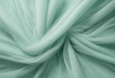 The primary subject of the image is a green curtain, which is the main object in the scene. The curtain is hanging in front of a green background, creating a visually appealing and cohesive scene. The image is a photo, capturing the details and colors of the curtain and the background. The overall atmosphere of the image is serene and calming, with the green color palette contributing to a sense of tranquility.