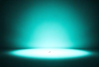 The primary subject of the image is a small, round light source, possibly a light bulb or a light emitting from a wall. The light source is located in the center of the image, surrounded by a blue background. The visual style of the image appears to be a photo, as it captures the light source in a realistic manner. The colors and mood of the image are predominantly blue, creating a calm and serene atmosphere.