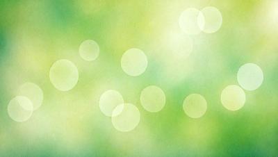 The primary subject of the image is a green background with a pattern of circles. The circles are of various sizes and are scattered throughout the background. The setting appears to be a natural environment, possibly a forest or a park. The visual style of the image is a combination of a photo and a digital art, as it has a slightly blurred appearance. The dominant colors in the image are green and white, creating a calm and serene atmosphere.