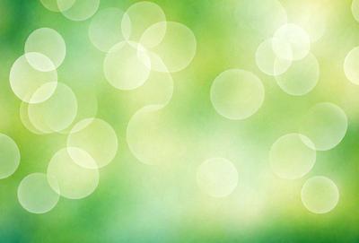 The primary subject of the image is a green background with a pattern of circles. The setting is a bright, lush green environment, which creates a vibrant and fresh atmosphere. The visual style is a combination of a photo and a digital art, as the circles have a slightly blurred appearance. The colors and mood of the image are predominantly green, with a hint of yellow, giving it a fresh and natural feel.
