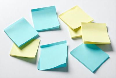 The primary subject of the image is a collection of yellow and blue sticky notes. The setting is a white table, and the visual style is a photo. The colors and mood of the image are predominantly yellow and blue, creating a calm and organized atmosphere.