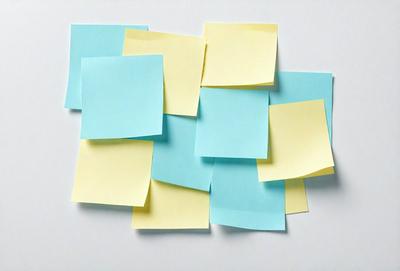 The primary subject of the image is a collection of yellow and blue sticky notes. These notes are arranged in various shapes and sizes, creating a visually interesting and colorful display. The setting is a white surface, which provides a clean and uncluttered backdrop for the sticky notes. The visual style of the image is a combination of photo and digital art, as the sticky notes appear to be digitally manipulated to create a unique and eye-catching arrangement. The dominant colors in the image are yellow and blue,