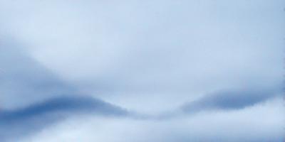 The primary subject of the image is a cloudy sky. The setting is a blue sky with clouds, and the visual style is a photo. The colors and mood of the image are predominantly blue and somewhat gloomy, as the sky is filled with clouds.