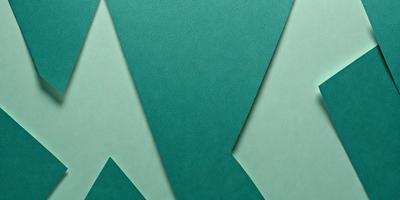 The primary subject of the image is a green background with a triangular shape. The setting is a green surface, possibly a wall or a piece of paper. The visual style is a close-up of the green triangular shape, which gives the image a clean and modern appearance. The colors and mood of the image are predominantly green, creating a calm and soothing atmosphere.