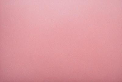 The primary subject of the image is a large, pink sheet of paper. The setting is a blank, red background, which creates a striking contrast with the pink paper. The visual style is a close-up of the paper, showcasing its texture and color. The colors and mood of the image are predominantly pink, giving it a warm and inviting atmosphere.