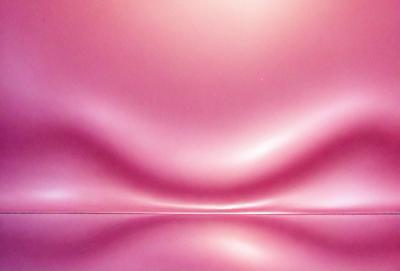 The primary subject of the image is a pink surface, which appears to be a curved or rounded surface. The setting is a room with a pink wall, and the visual style is a close-up of the pink surface. The colors and mood of the image are predominantly pink, creating a warm and inviting atmosphere.