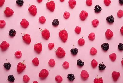 The primary subject of the image is a close-up of a bunch of red raspberries. The setting is a pink background, which adds a vibrant and fresh touch to the scene. The visual style is a close-up of the raspberries, showcasing their details and texture. The colors and mood of the image are predominantly pink and red, creating a warm and inviting atmosphere.