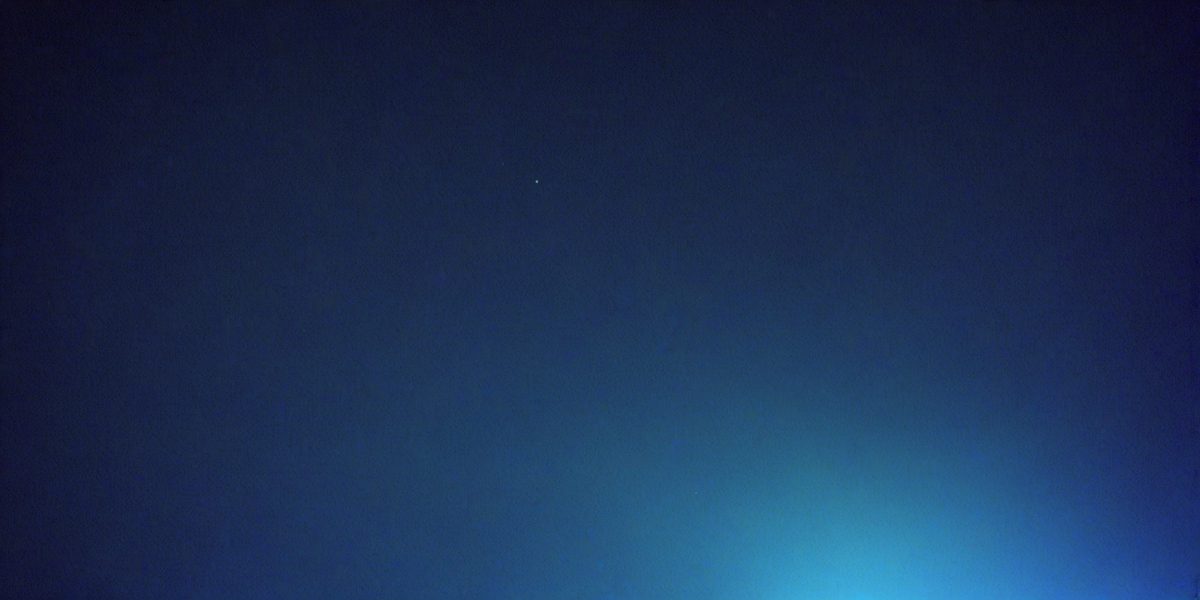 The primary subject of the image is the night sky, which is filled with stars. The setting is a dark, cloudy night, with the sky being the main focus of the image. The visual style is a photo, capturing the beauty of the night sky. The colors and mood of the image are predominantly dark and moody, with the stars providing a sense of depth and tranquility.