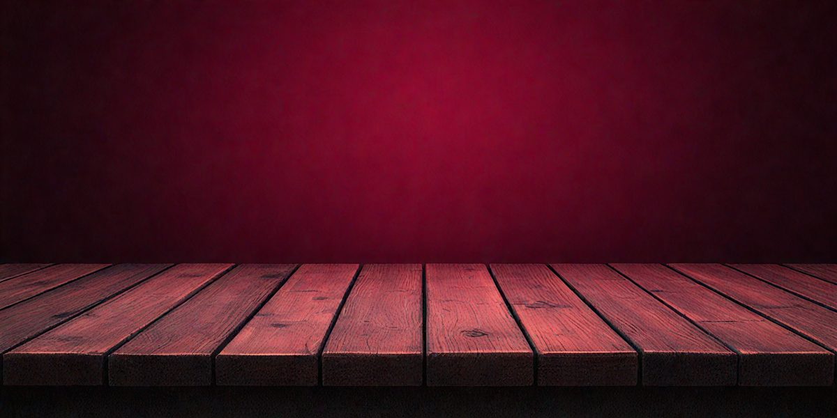 The primary subject of the image is a wooden bench with a red surface. The setting is a red wall, which serves as the background. The visual style is a photo, capturing the bench and the red wall in a realistic manner. The colors and mood of the image are predominantly red, creating a warm and inviting atmosphere.