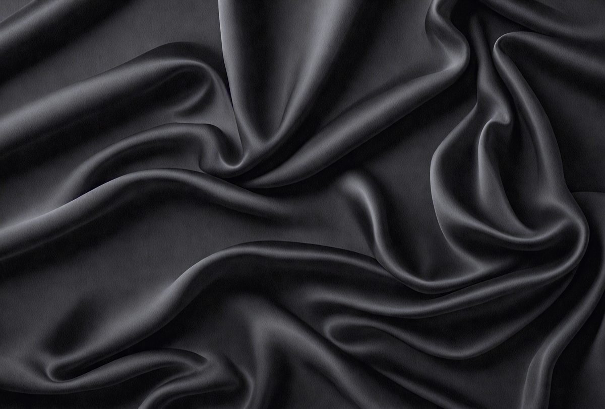 The primary subject of the image is a close-up of a black fabric, possibly a piece of clothing or a curtain. The setting is a dark background, which emphasizes the fabric's texture and color. The visual style appears to be a photo, as it captures the fabric's details and texture. The colors and mood of the image are predominantly dark, with the black fabric being the main focus.