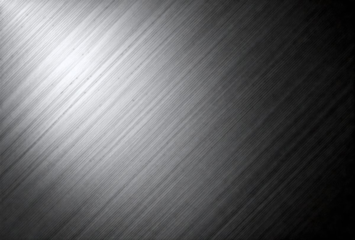 The primary subject of the image is a silver surface, which appears to be a metal wall or a shiny metal sheet. The setting is a black background, which contrasts with the silver surface. The visual style is a close-up of the silver surface, showcasing its texture and reflective properties. The colors and mood of the image are predominantly silver and black, creating a sleek and modern atmosphere.