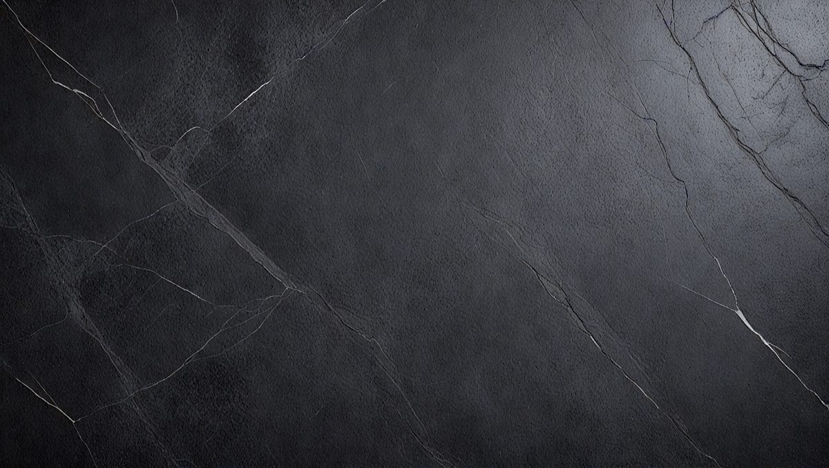 The primary subject of the image is a black marble countertop. The setting is a kitchen, with the countertop being the main focus of the scene. The visual style is a photo, capturing the details and texture of the marble countertop. The colors and mood of the image are predominantly dark, with the black marble providing a sleek and sophisticated appearance.