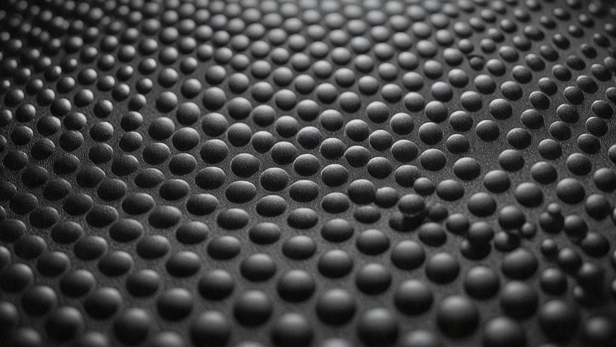 The primary subject of the image is a close-up of a black and white patterned surface, which appears to be a textured material. The setting is a black background, and the visual style is a close-up of the pattern. The colors and mood of the image are predominantly black and white, giving it a classic and timeless appearance.