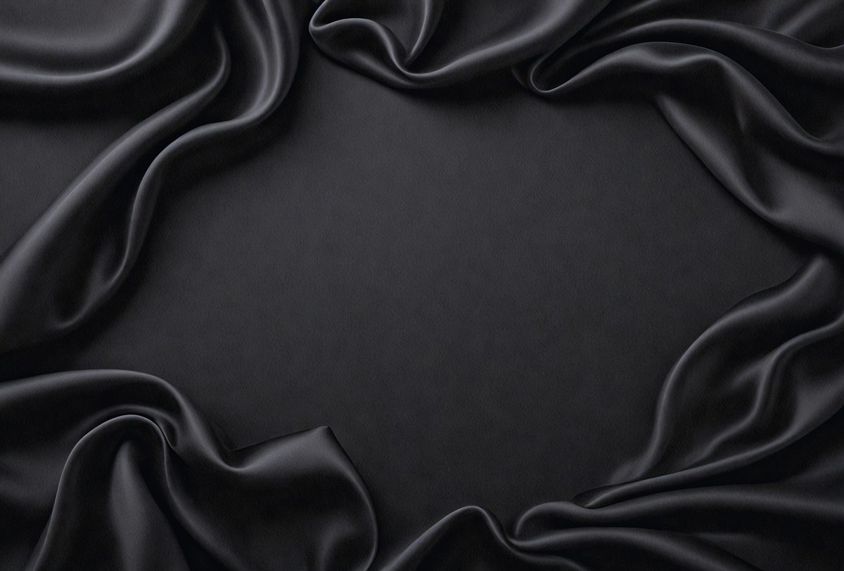 The primary subject of the image is a black cloth, which is the main object, scene, or focus of the image. The setting or background is a black surface, and the visual style is a photo. The colors and mood of the image are predominantly black, creating a dark and moody atmosphere.