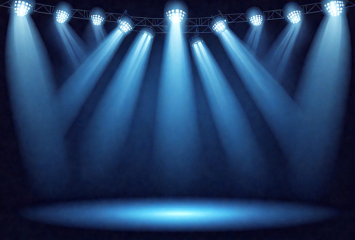 The primary subject of the image is a stage with a blue light shining on it. The setting is a darkened stage, and the visual style is a photo. The dominant colors are blue and black, creating a moody atmosphere.